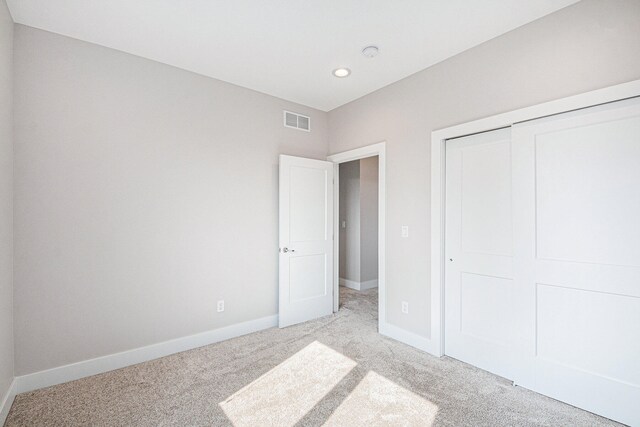 unfurnished bedroom featuring light carpet and a closet