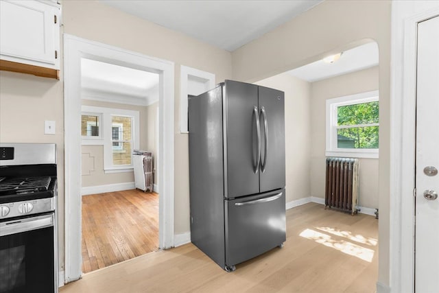 kitchen with radiator, stainless steel appliances, and light wood-type flooring