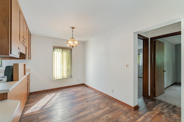 unfurnished dining area featuring dark wood-type flooring and a notable chandelier