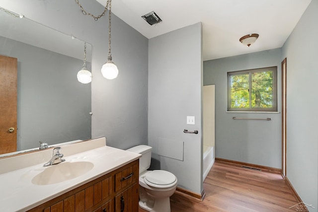 bathroom with a tub to relax in, vanity, hardwood / wood-style flooring, and toilet