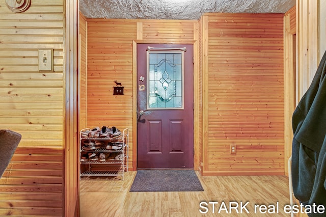 entrance foyer featuring hardwood / wood-style flooring and wooden walls