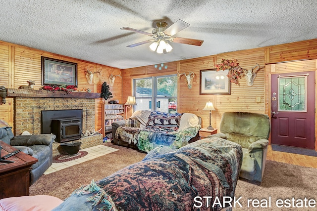 living room with a textured ceiling, wooden walls, ceiling fan, and a wood stove