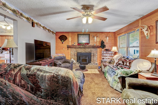 carpeted living room featuring ceiling fan, wooden walls, a textured ceiling, and a wood stove