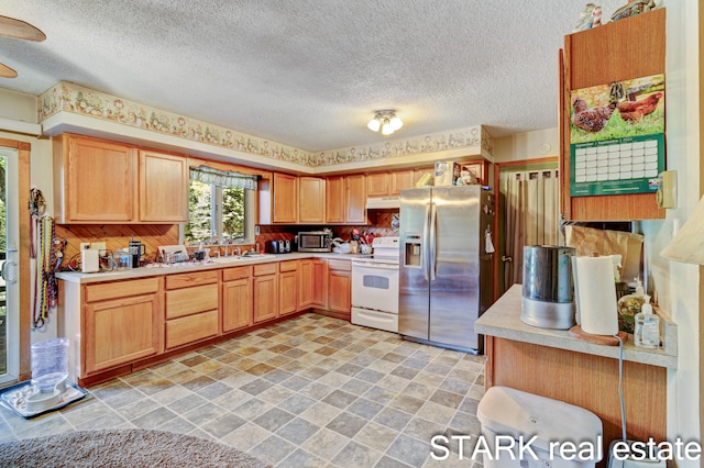 kitchen featuring light brown cabinetry, sink, stainless steel appliances, and a textured ceiling