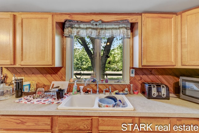 kitchen with sink, wooden walls, and light brown cabinets