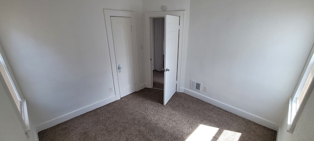 unfurnished bedroom with dark carpet