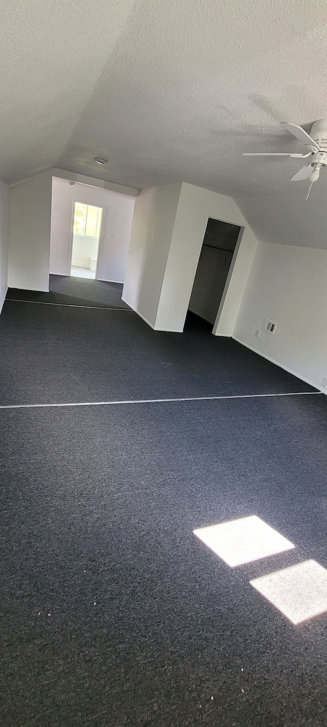 additional living space with a textured ceiling, ceiling fan, and lofted ceiling