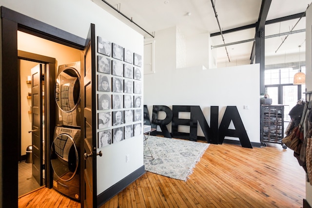 foyer entrance with wood-type flooring, a high ceiling, and stacked washer / dryer
