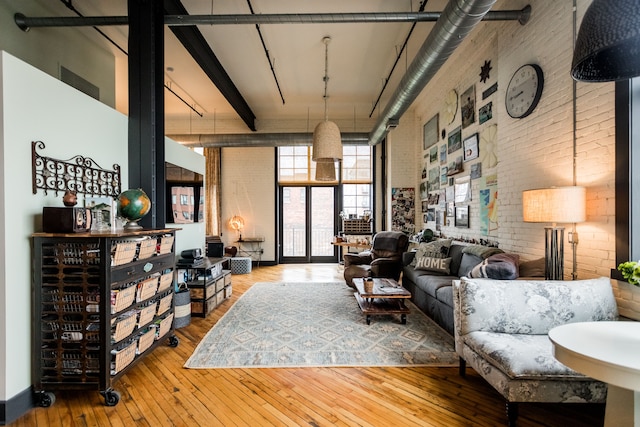 living area featuring brick wall, a towering ceiling, and hardwood / wood-style floors