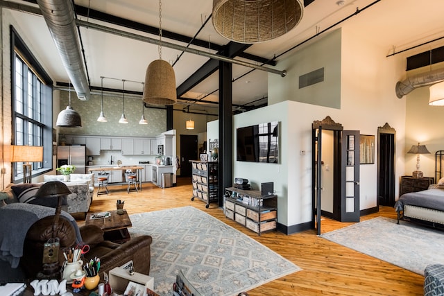 living area featuring visible vents, light wood-style flooring, and a high ceiling