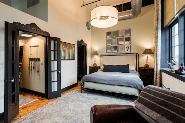 bedroom with visible vents, wood finished floors, and a towering ceiling