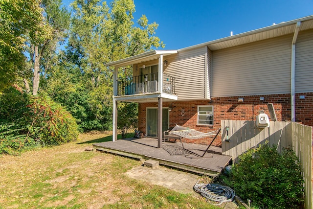 back of house with a balcony, a deck, and a yard