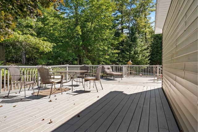 1100 Tisdale Rd, Roscommon, MI 48653 - wooden terrace with view of scattered trees and outdoor dining area