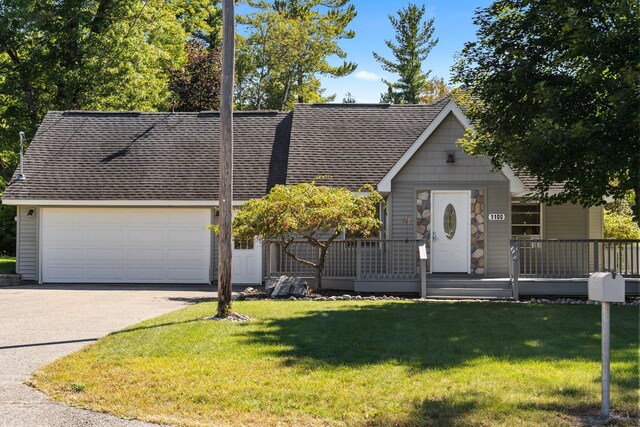 1100 Tisdale Rd, Roscommon, MI 48653 - view of front of home featuring roof with shingles, asphalt driveway, a front yard, a porch, and a garage