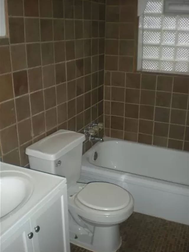 full bathroom featuring vanity, toilet, tile walls, and bathtub / shower combination