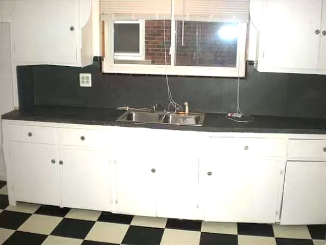 kitchen with backsplash, white cabinetry, and sink