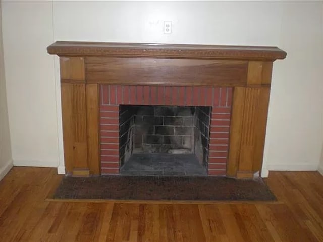 interior details featuring wood-type flooring and a brick fireplace