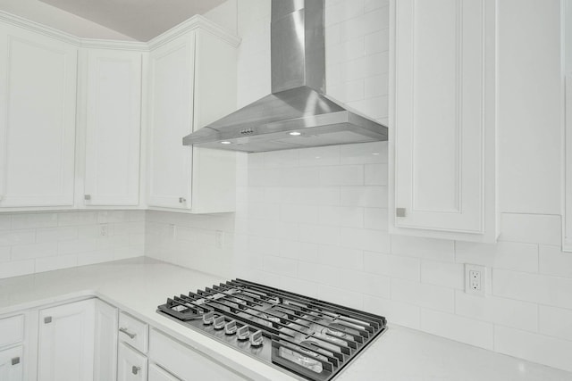 kitchen featuring white cabinets, wall chimney exhaust hood, backsplash, and gas cooktop