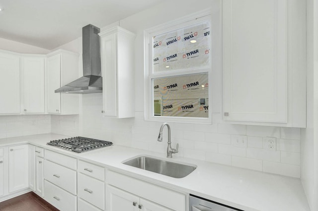 kitchen featuring decorative backsplash, wall chimney exhaust hood, sink, white cabinets, and stainless steel gas stovetop