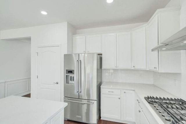 kitchen featuring backsplash, dark wood-type flooring, wall chimney exhaust hood, white cabinetry, and stainless steel appliances