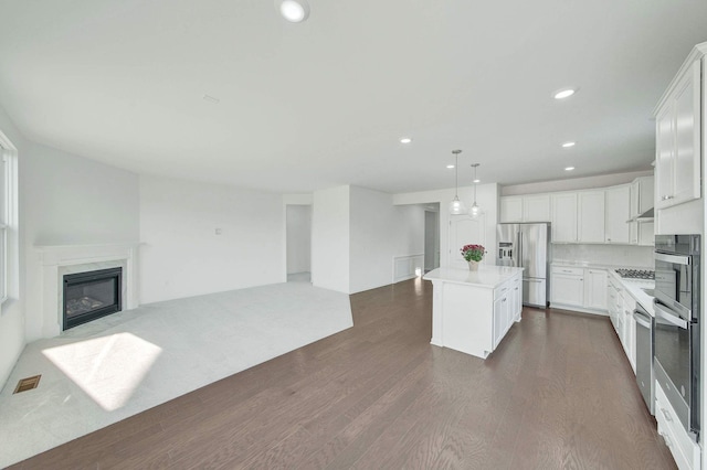 kitchen featuring white cabinetry, dark wood-type flooring, pendant lighting, a kitchen island, and appliances with stainless steel finishes