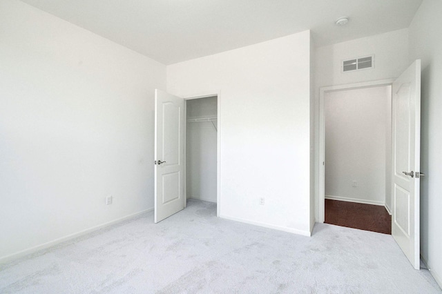 unfurnished bedroom featuring light carpet and a closet