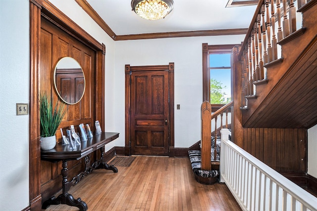 foyer entrance featuring wood-type flooring, crown molding, and an inviting chandelier