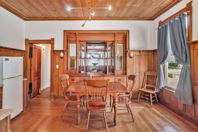 dining area with wooden walls, light hardwood / wood-style floors, crown molding, and wooden ceiling