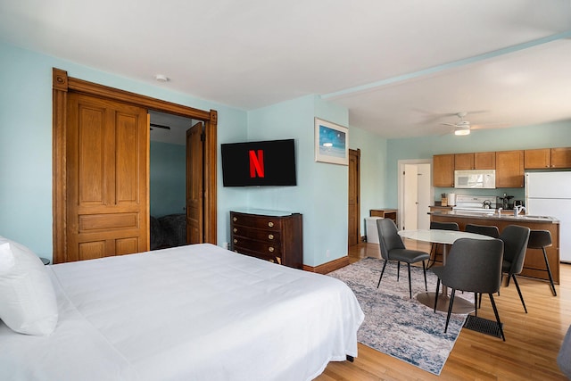 bedroom with ceiling fan, light wood-type flooring, and white refrigerator