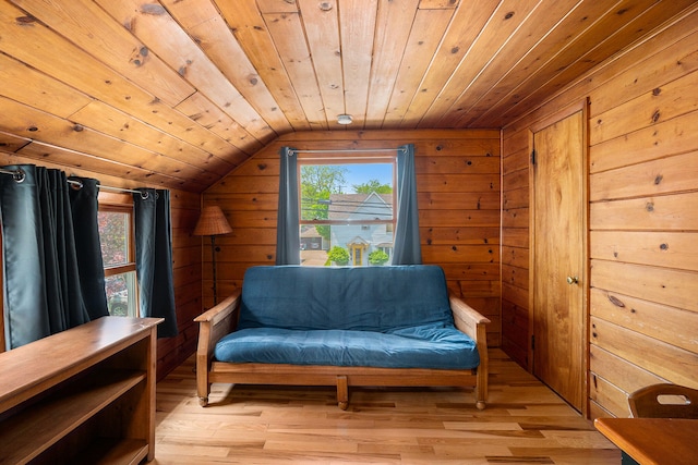 living area featuring wooden walls, light hardwood / wood-style flooring, and vaulted ceiling