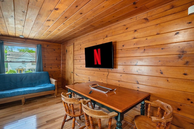 dining area with wooden walls, wood ceiling, and light wood-type flooring