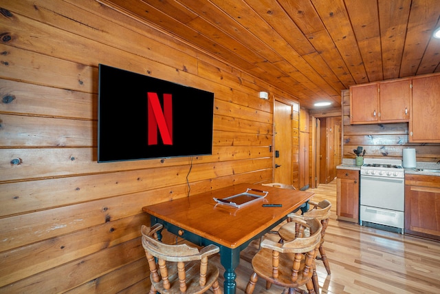 dining area with wood walls, light hardwood / wood-style flooring, and wood ceiling