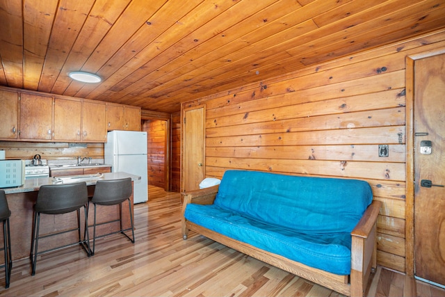 sitting room with sink, light hardwood / wood-style floors, wooden walls, and wood ceiling