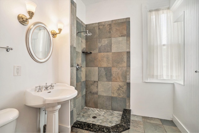 bathroom with a tile shower and toilet