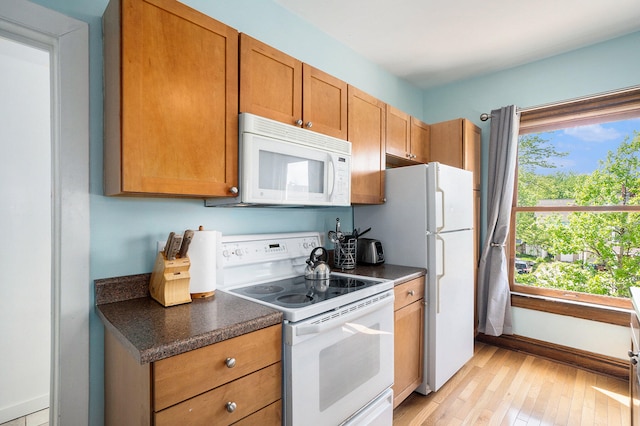 kitchen featuring plenty of natural light, light wood-type flooring, and white appliances