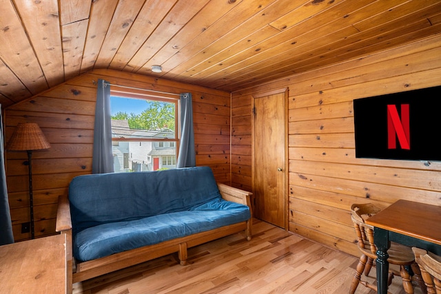 living area with light wood-type flooring, vaulted ceiling, wooden ceiling, and wood walls