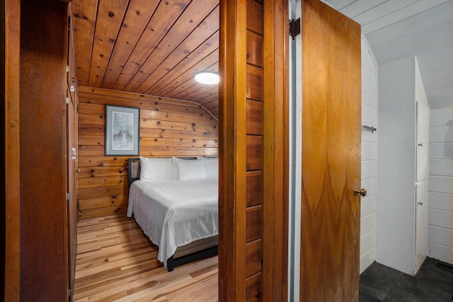 bedroom with light wood-type flooring, wooden walls, lofted ceiling, and wood ceiling