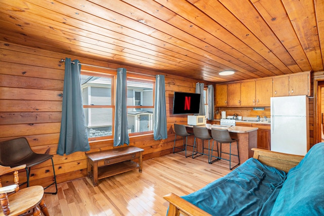 kitchen featuring wooden ceiling, white refrigerator, wood walls, a breakfast bar area, and light wood-type flooring