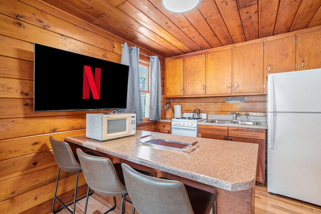 kitchen featuring wood walls, sink, light hardwood / wood-style floors, and white appliances