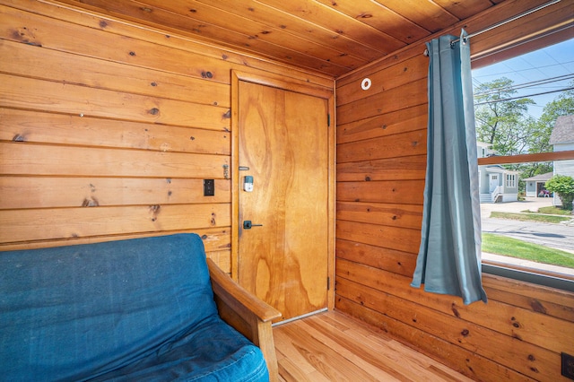 unfurnished room with wood-type flooring, wooden ceiling, and wood walls