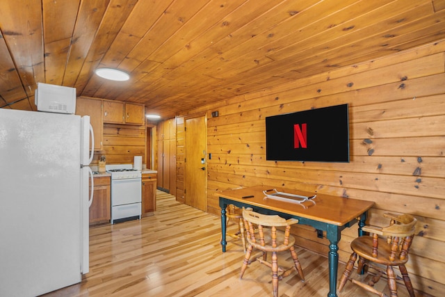 dining space featuring light wood-type flooring, wooden walls, and wooden ceiling