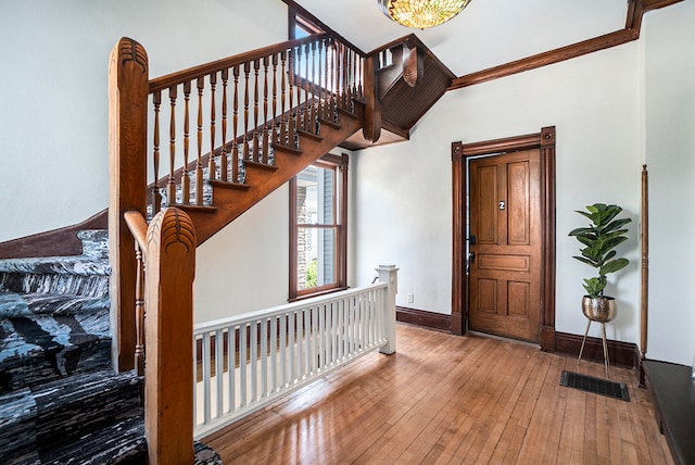 foyer entrance with crown molding and wood-type flooring