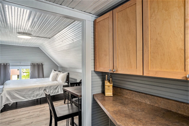 bedroom featuring wood walls, light hardwood / wood-style flooring, and lofted ceiling