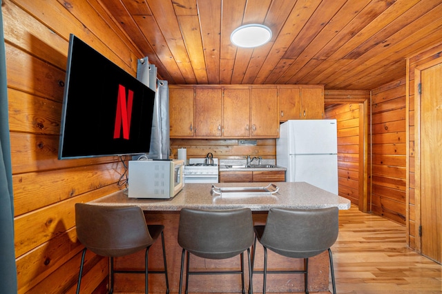 kitchen featuring wood ceiling, white appliances, sink, light hardwood / wood-style floors, and wood walls