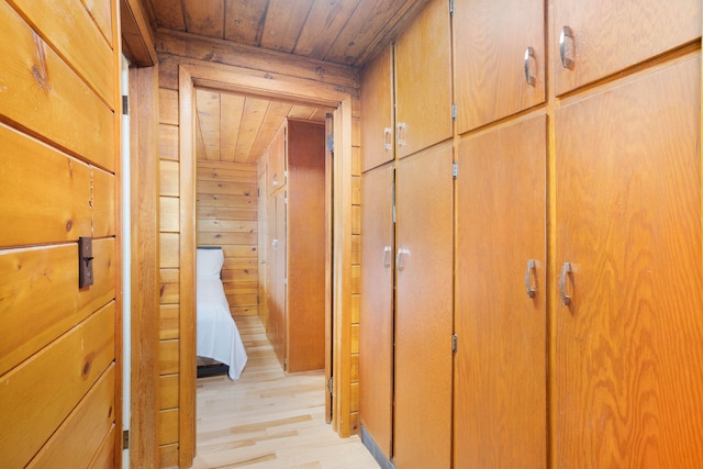 hall with wood walls, wooden ceiling, and light wood-type flooring