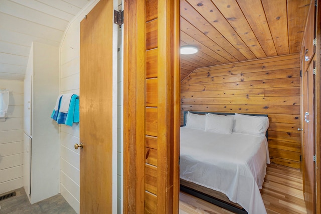 bedroom with light hardwood / wood-style flooring, vaulted ceiling, wood ceiling, and wood walls