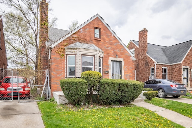 8594 Lauder St, Detroit, MI 48228 - view of front facade featuring brick siding, a chimney, a shingled roof, and driveway