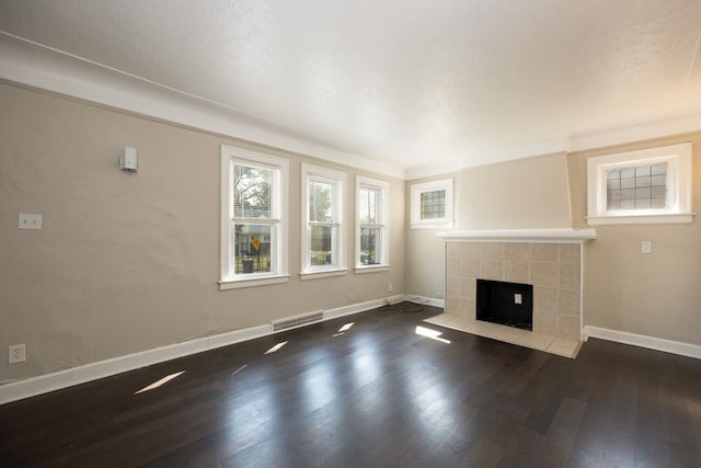 unfurnished living room featuring dark hardwood / wood-style flooring, a textured ceiling, and a tile fireplace