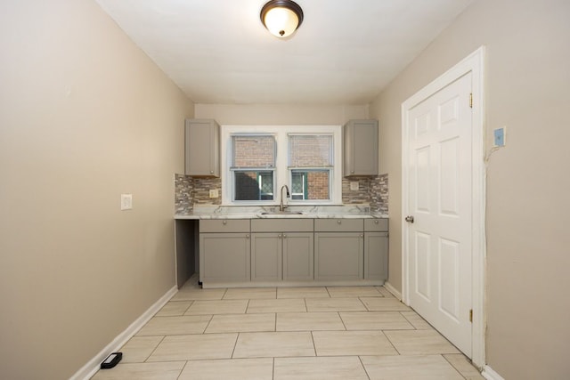 kitchen with decorative backsplash, gray cabinetry, and sink