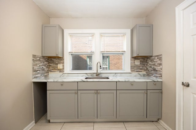 kitchen featuring gray cabinetry, decorative backsplash, sink, and light stone countertops